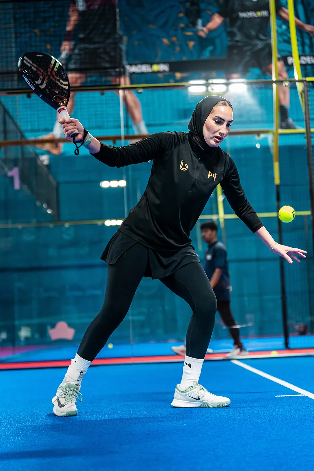 لاعبة تردّ الكرة من خلف الملعب